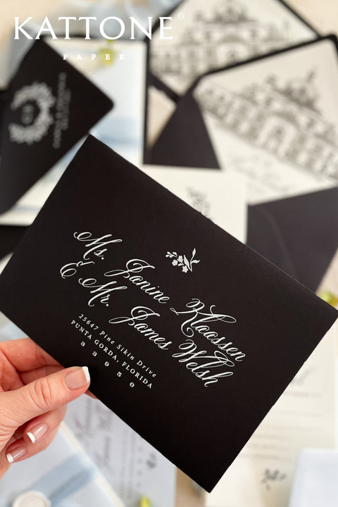 Close-up of white ink address printing on black envelope showing crisp lettering and refined contrast against matte cardstock.