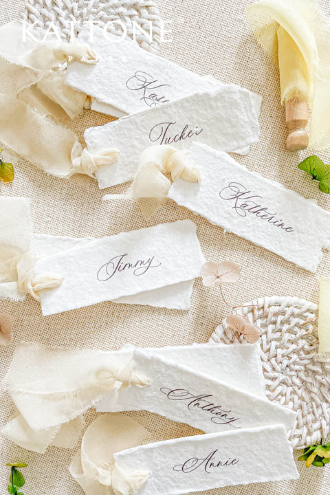 Add a touch of effortless elegance to your event with our handmade paper place cards, featuring natural deckled edges, soft ivory chiffon ribbon, and refined calligraphy. Each card is delicately crafted to elevate your wedding tablescape with a romantic, airy, and organic aesthetic. Perfect for fine-art weddings, garden celebrations, and timeless event styling.