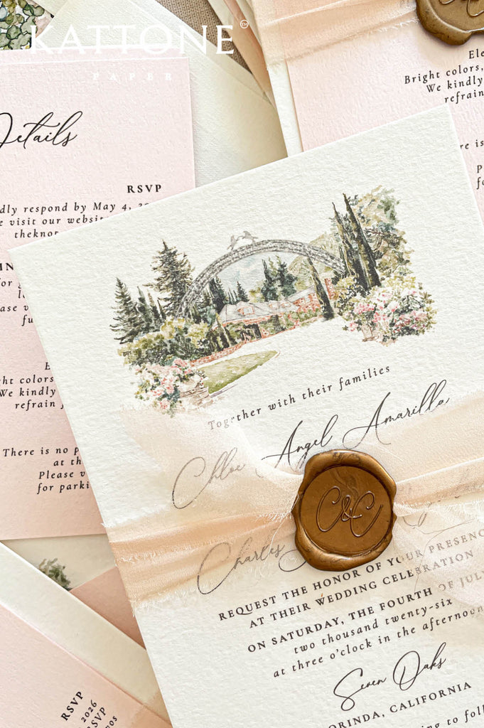 Close-up of handmade paper wedding invitation featuring a watercolor illustration of a garden wedding venue and elegant typography.