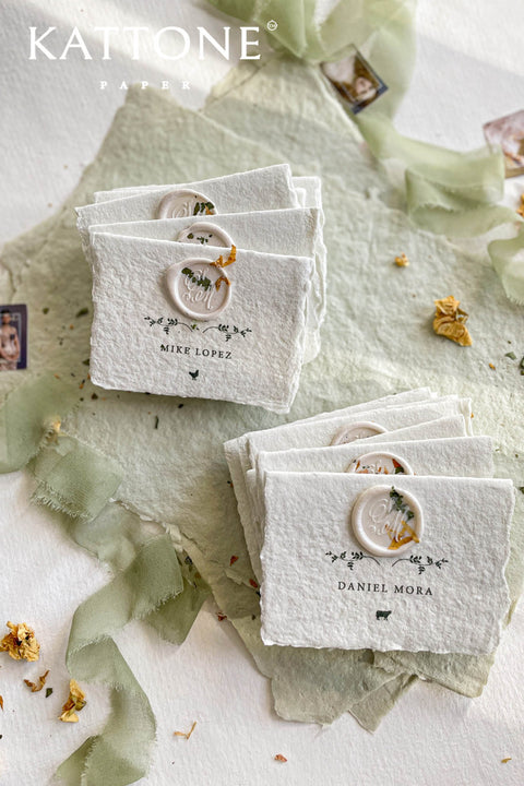 Elevate your table setting with our fine-art handmade paper place cards, each adorned with an elegant pressed-flower wax seal and delicate botanical artwork. Crafted from luxury deckled-edge cotton paper, these name cards bring a romantic, organic charm to weddings, garden celebrations, and intimate events. Their soft sage tones and artisanal texture create an unforgettable, heirloom-quality detail for your guests.