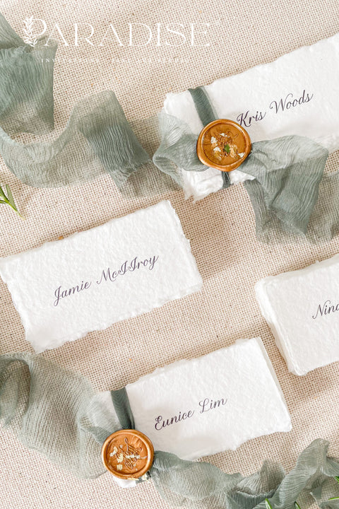 Enhance your tablescape with our handmade paper place cards, crafted from luxurious cotton rag paper and finished with naturally torn deckled edges. Each card features elegant calligraphy, soft hand-dyed ribbon, and the option of a wax seal for added fine-art charm. Perfect for weddings, engagement parties, showers, and upscale events, these artisanal place cards bring texture, romance, and sophistication to every setting.