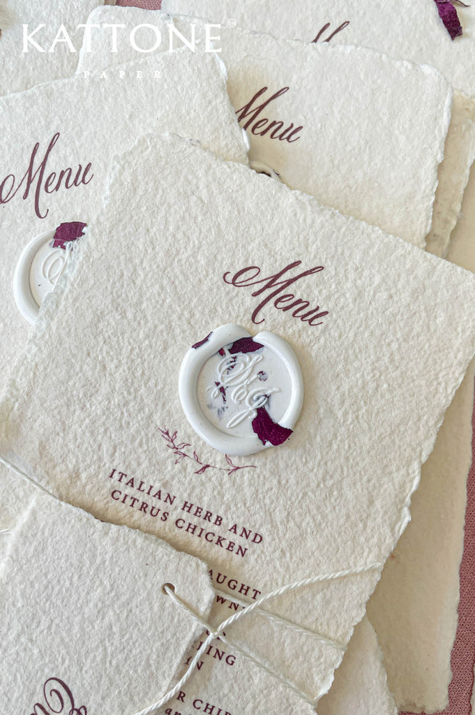 Close-up of handmade paper wedding menu with matching place name tag and elegant calligraphy typography.