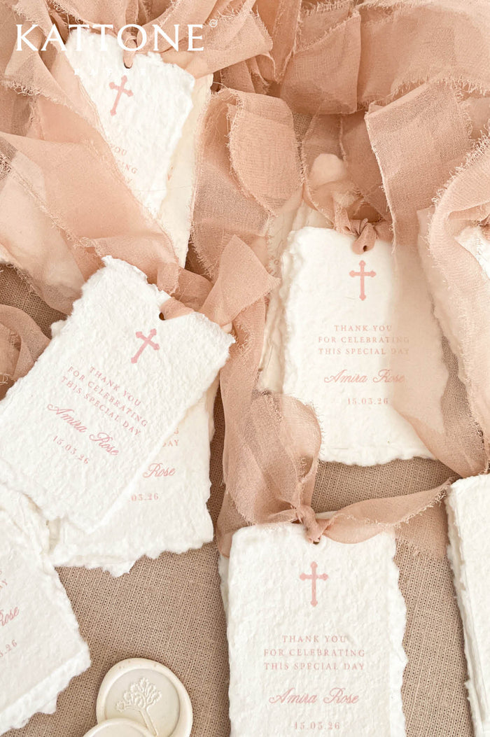 Handmade wedding thank you cards with deckled edge cotton paper, blush pink text and small cross detail tied with soft chiffon ribbon.