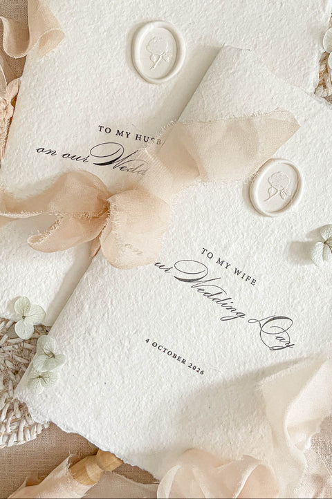 Luxury handmade paper wedding vows booklet featuring deckled edge cotton paper, elegant typography, chiffon ribbon ties, and wax seal accents.
