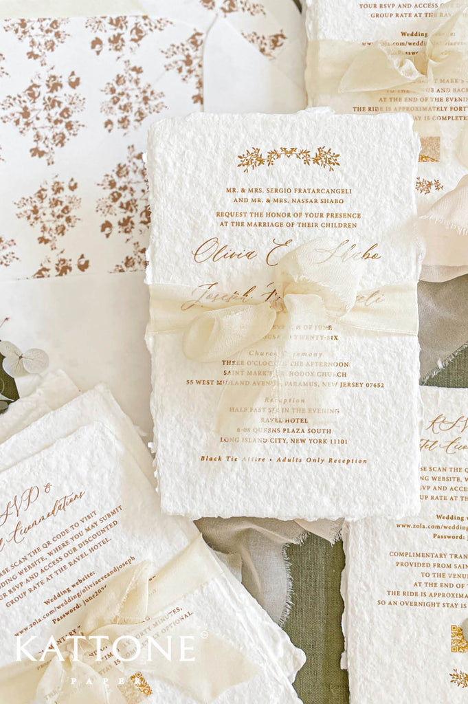 Close up of handmade cotton paper invitation showing textured deckled edges, soft floral motifs and elegant typography in warm neutral tones.