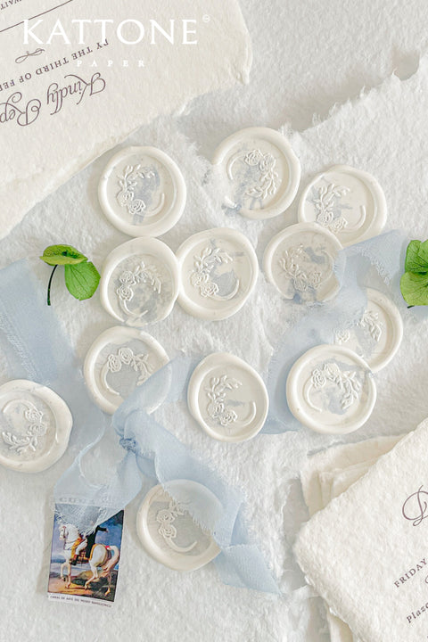 Hand-poured wax seals designed to add a soft, romantic finish to wedding stationery, envelopes, and heirloom keepsakes. Featuring an intricate floral crest pressed into creamy white wax, each seal offers timeless elegance with a tactile, artisanal feel. Perfect for couples seeking refined details that elevate their invitations, vows, or correspondence into something truly memorable.