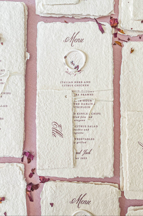 Close-up of handmade paper wedding menu with matching place name tag and elegant calligraphy typography.