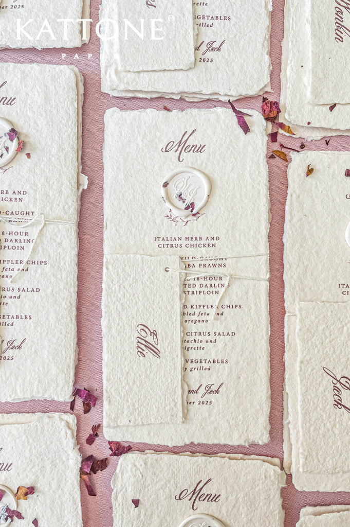 Close-up of handmade paper wedding menu with matching place name tag and elegant calligraphy typography.