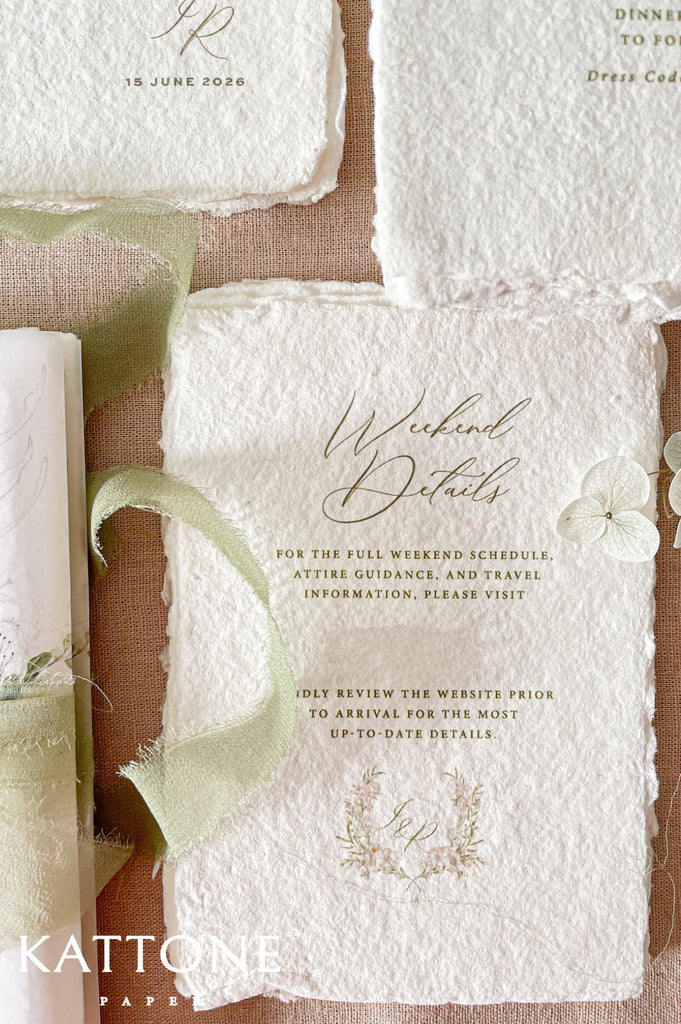 Elegant handmade cotton paper wedding invitation with deckled edges featuring refined script typography, delicate botanical monogram details, and soft neutral styling.