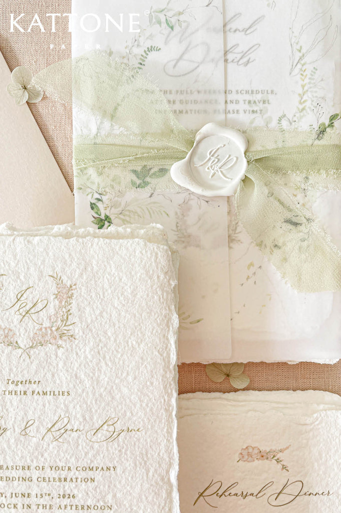 Soft sage chiffon ribbon wrapped around vellum-covered wedding stationery finished with a personalized ivory wax seal.