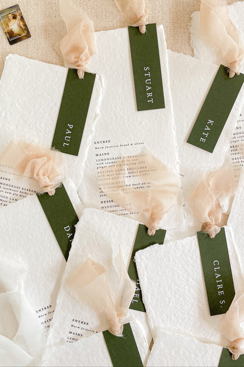 Make every seat a statement with our handmade paper wedding menus, featuring personalized name tags, soft ribbons, and deckled edges. Each menu is crafted on luxury cotton rag paper for a fine art look that’s both organic and sophisticated - ideal for modern, romantic, or nature-inspired weddings. Thoughtfully designed to blend function and beauty, these menus elevate your reception with artisanal charm and timeless elegance.