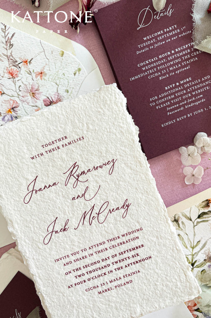 Close up of textured handmade cotton paper wedding invitation showing organic deckled edges and elegant burgundy script typography.