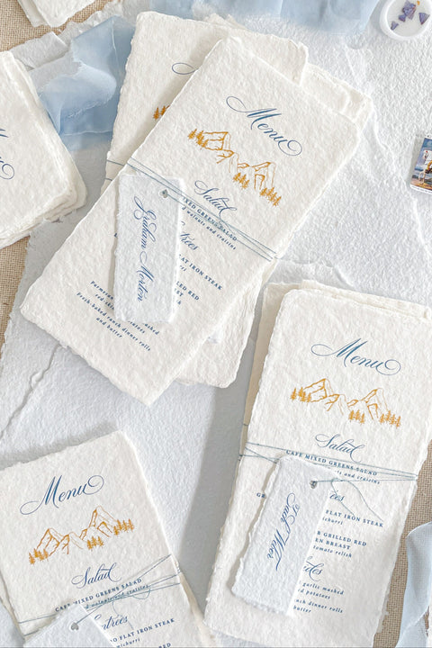Capture timeless mountain charm with our handmade paper wedding menus, featuring soft deckled edges, textured cotton paper, and elegant alpine illustrations. Each piece is hand-pressed with artisanal care, pairing nature-inspired design with fine typography for an effortlessly elevated tablescape. Perfect for destination, outdoor, or rustic-elegant weddings, these menus bring natural sophistication to every detail.