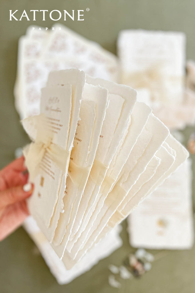 Handmade cotton paper with visible fibers and organically torn deckled edges highlighting artisanal craftsmanship.