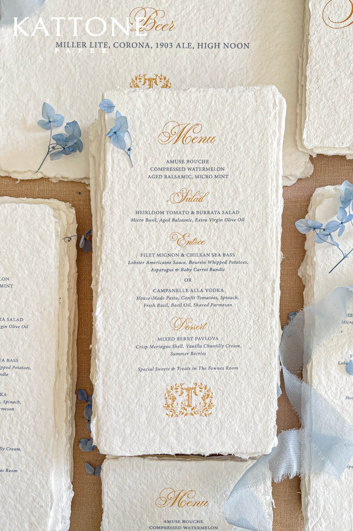Luxury handmade paper wedding menus featuring deckled edge cotton paper, elegant gold script headings, blue typography, and delicate floral styling.