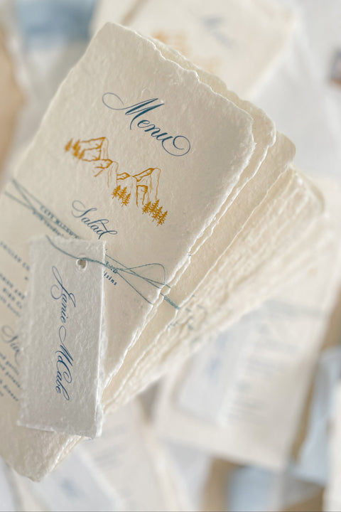 Capture timeless mountain charm with our handmade paper wedding menus, featuring soft deckled edges, textured cotton paper, and elegant alpine illustrations. Each piece is hand-pressed with artisanal care, pairing nature-inspired design with fine typography for an effortlessly elevated tablescape. Perfect for destination, outdoor, or rustic-elegant weddings, these menus bring natural sophistication to every detail.