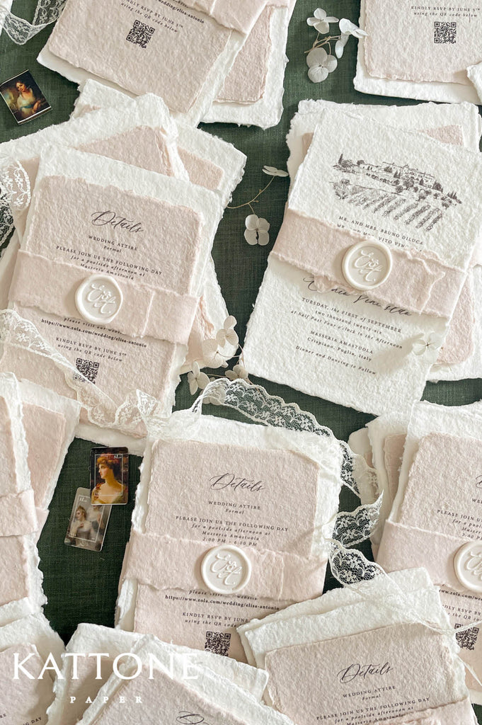 Fine art wedding invitation suite styled in a flat lay with handmade paper invitations, envelopes, lace accents and coordinated stationery pieces.