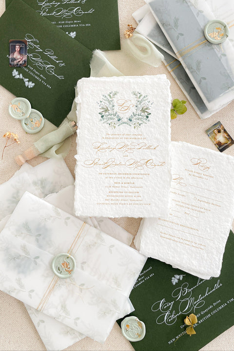 Set a festive and romantic tone for your winter celebration with this exquisite wedding invitation suite. This collection features a beautiful Christmas watercolor monogram of your initials, creating a personalized and seasonal touch. Each invitation is elegantly enclosed in a translucent vellum jacket and sealed with a custom wax seal that includes a delicate golden leaf, adding a luxurious and elegant finish that your guests will adore.
