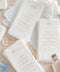 These handmade paper wedding menus embody effortless sophistication and artisanal beauty. Each piece is crafted from luxurious 100% cotton rag paper, featuring naturally deckled edges and a tactile texture that evokes fine art elegance. The menus are adorned with gold calligraphy-style text, creating a graceful contrast against the soft white handmade paper - a perfect fusion of classic romance and modern refinement.