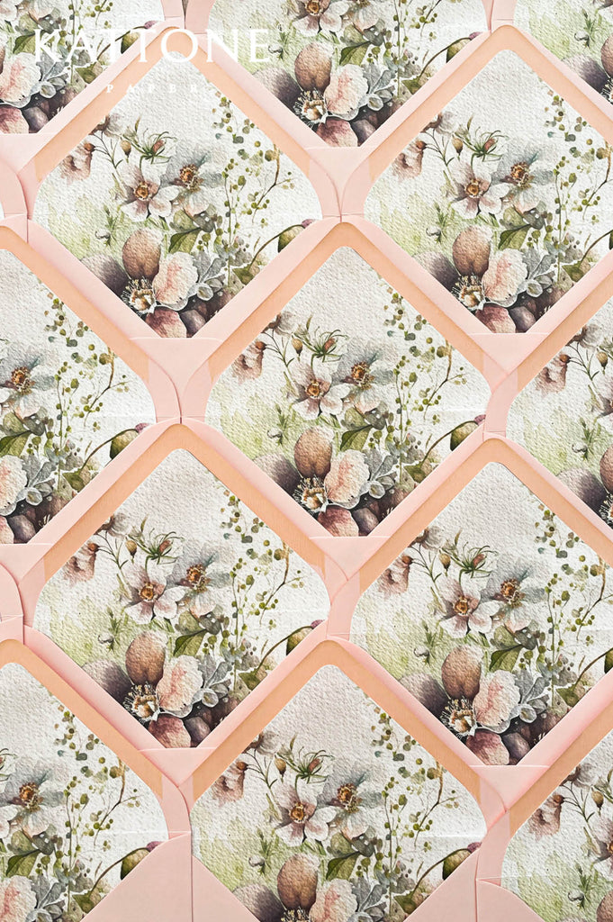 Blush pink wedding envelopes with botanical watercolor envelope liners featuring delicate floral illustrations and soft greenery.