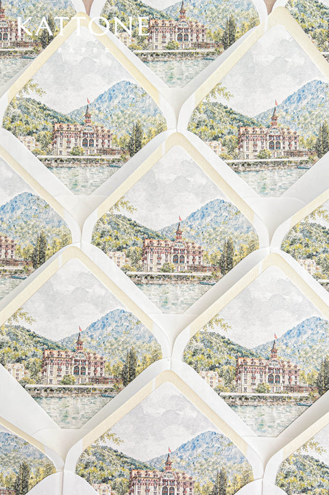 Overhead arrangement of elegant white wedding envelopes featuring illustrated watercolor liners with an Alpine mountain landscape, historic waterfront hotel, peaceful lake, and surrounding greenery. The repeating scenic design, soft ivory envelope borders, and delicate hand-painted details create a coordinated collection of luxury destination wedding envelopes for an elegant European lakeside wedding.