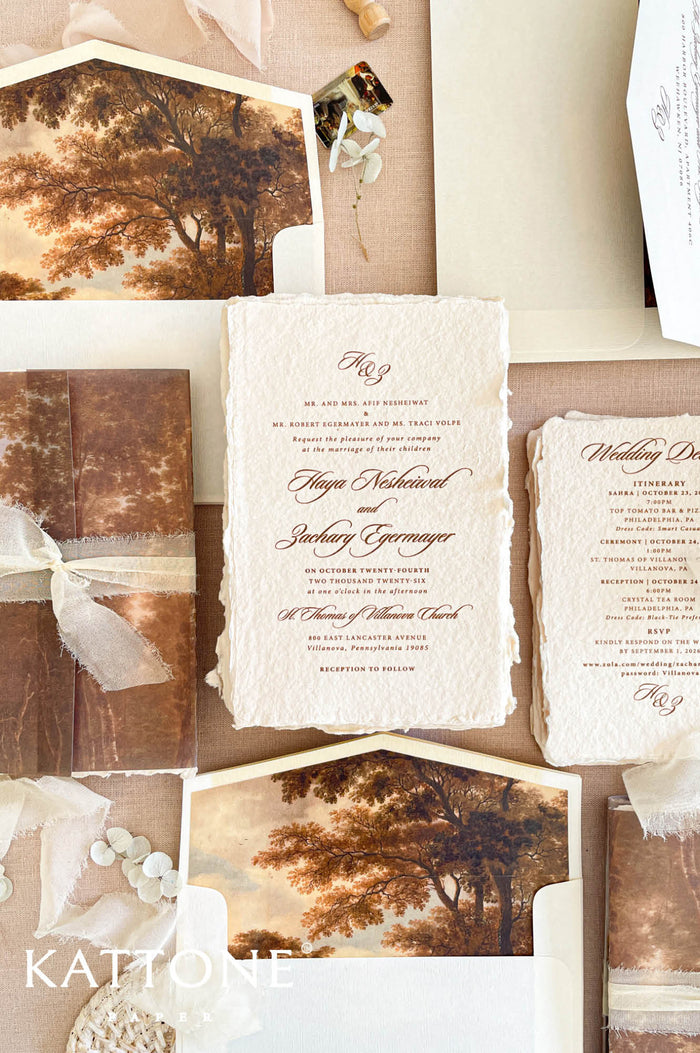 Luxury handmade paper wedding invitation suite featuring deckled edge cotton paper, elegant calligraphy typography, custom scenic vellum wraps, and warm autumn-inspired fine art wedding stationery.