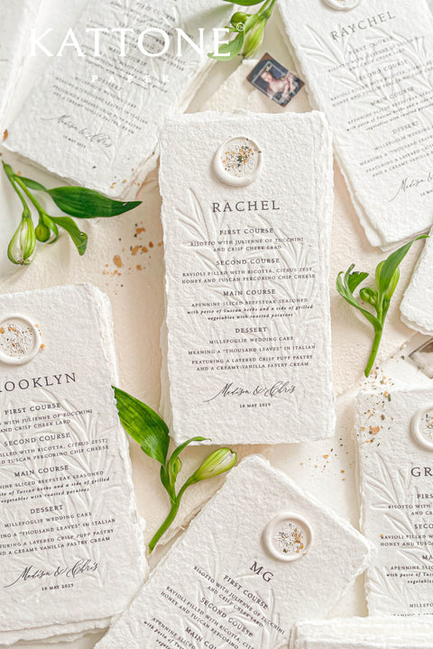 These embossed handmade paper wedding menus embody the essence of refined elegance and timeless artistry. Each piece is crafted from 100% cotton rag paper, known for its organic texture and signature deckled edges that add an artisanal, heirloom feel. The design features delicate blind embossing of botanical motifs, adding soft dimension and sophistication, while luxurious typography in classic ink beautifully contrasts the natural paper’s tactile surface.