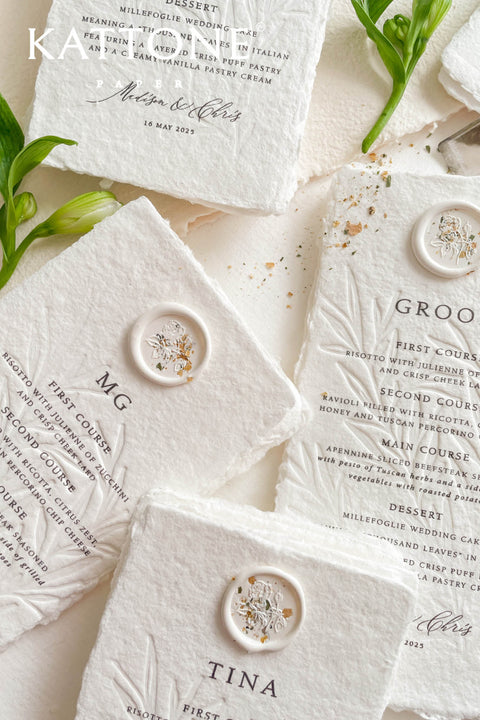 These embossed handmade paper wedding menus embody the essence of refined elegance and timeless artistry. Each piece is crafted from 100% cotton rag paper, known for its organic texture and signature deckled edges that add an artisanal, heirloom feel. The design features delicate blind embossing of botanical motifs, adding soft dimension and sophistication, while luxurious typography in classic ink beautifully contrasts the natural paper’s tactile surface.