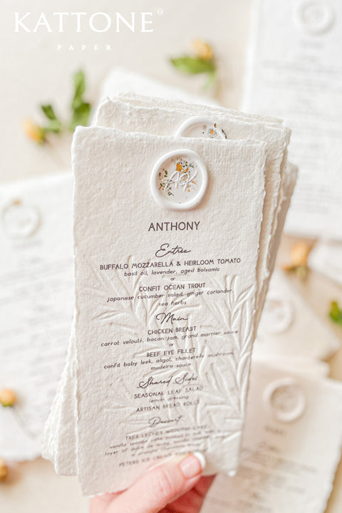 Elevate your wedding table with our embossed handmade paper menus, where timeless craftsmanship meets modern refinement. Each menu is printed on 100% cotton handmade paper with delicate deckled edges and a subtle botanical embossing, creating a tactile experience of understated luxury. Finished with an elegant floral wax seal personalized for each guest, these menus add an exquisite fine-art touch to your reception decor.