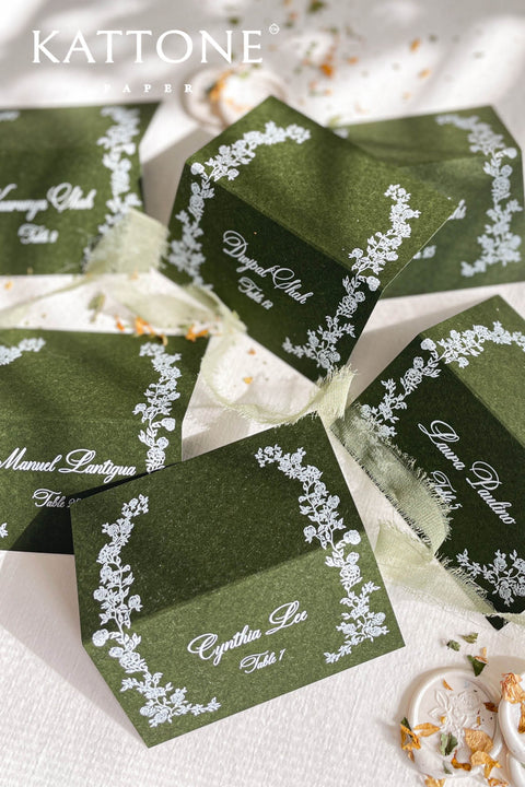 Elevate your tablescape with our elegant forest green place cards featuring delicate white floral illustrations and refined handwritten-style lettering. Crafted on premium cardstock, each folded card brings depth, contrast, and timeless sophistication to your wedding or special event. Perfect for modern, botanical, and luxury themes, these place cards add a polished and cohesive finishing touch to guest seating.