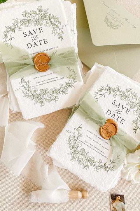 Announce your wedding with timeless elegance through our handmade paper Save the Date cards, adorned with a botanical wreath illustration in soft green tones and finished with a silk ribbon and wax seal. Each piece is printed on luxury 100% cotton handmade paper with natural deckled edges, offering a fine-art, heirloom-quality aesthetic perfect for romantic, garden-inspired weddings.