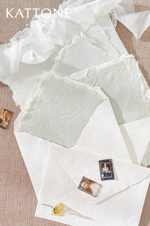 Handmade paper envelopes with envelope liners styled on textured fabric with silk ribbon and fine art wedding stationery details.
