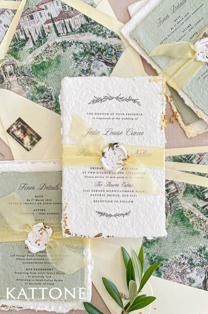 Hand-applied gold leaf edging along the deckled edges of handmade wedding invitation adding a luxurious finish.