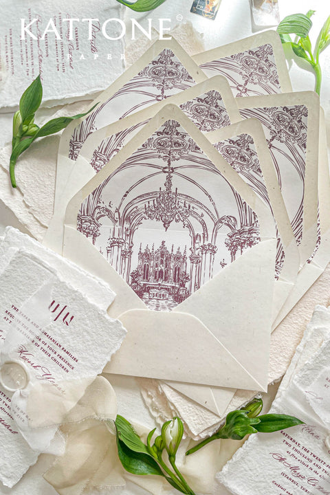 Wedding envelopes with hand-drawn venue envelope liners styled with handmade paper, greenery, and fine art wedding stationery details.