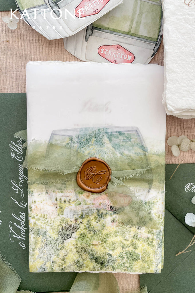 Soft translucent vellum wrap printed with custom watercolor landscape artwork layered over handmade paper invitations, creating dimension, softness, and elevated luxury presentation.