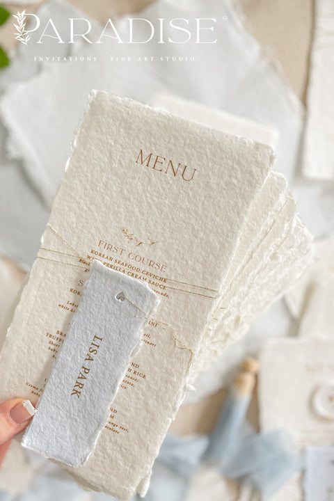 These handmade paper wedding menus are the embodiment of fine art elegance - timeless, refined, and delicately handcrafted. Made from 100% cotton rag paper, each menu showcases naturally deckled edges and a soft, tactile surface that enhances its artisanal charm. The design features gold-printed text, a minimalist layout, and a custom wax seal with gold leaf detailing, paired with a personalized name tag for each guest - seamlessly combining beauty and function.