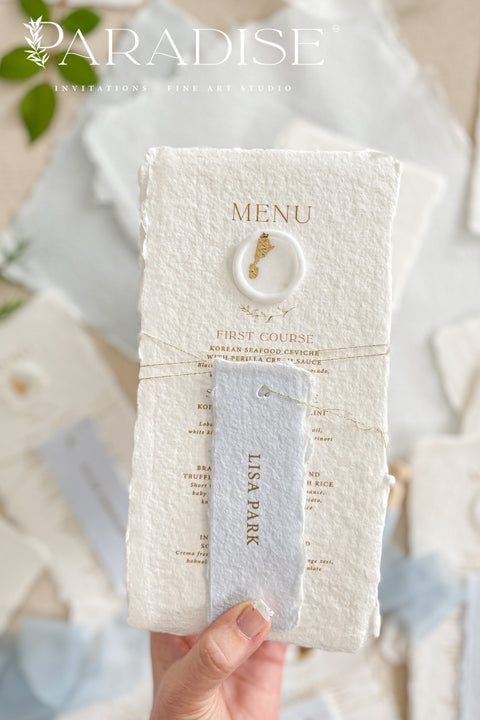 These handmade paper wedding menus are the embodiment of fine art elegance - timeless, refined, and delicately handcrafted. Made from 100% cotton rag paper, each menu showcases naturally deckled edges and a soft, tactile surface that enhances its artisanal charm. The design features gold-printed text, a minimalist layout, and a custom wax seal with gold leaf detailing, paired with a personalized name tag for each guest - seamlessly combining beauty and function.