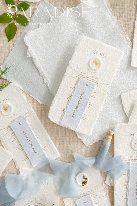 These handmade paper wedding menus are the embodiment of fine art elegance - timeless, refined, and delicately handcrafted. Made from 100% cotton rag paper, each menu showcases naturally deckled edges and a soft, tactile surface that enhances its artisanal charm. The design features gold-printed text, a minimalist layout, and a custom wax seal with gold leaf detailing, paired with a personalized name tag for each guest - seamlessly combining beauty and function.