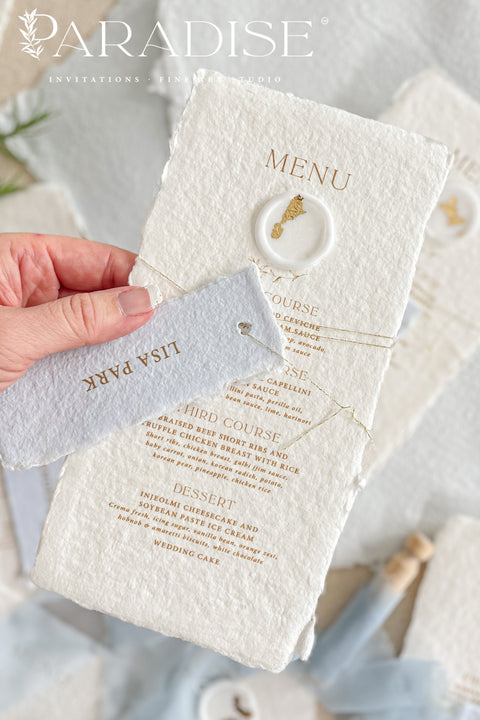 These handmade paper wedding menus are the embodiment of fine art elegance - timeless, refined, and delicately handcrafted. Made from 100% cotton rag paper, each menu showcases naturally deckled edges and a soft, tactile surface that enhances its artisanal charm. The design features gold-printed text, a minimalist layout, and a custom wax seal with gold leaf detailing, paired with a personalized name tag for each guest - seamlessly combining beauty and function.