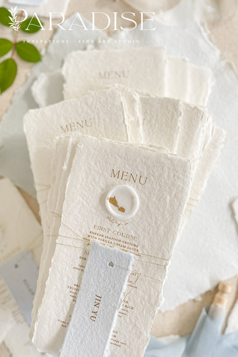 These handmade paper wedding menus are the embodiment of fine art elegance - timeless, refined, and delicately handcrafted. Made from 100% cotton rag paper, each menu showcases naturally deckled edges and a soft, tactile surface that enhances its artisanal charm. The design features gold-printed text, a minimalist layout, and a custom wax seal with gold leaf detailing, paired with a personalized name tag for each guest - seamlessly combining beauty and function.