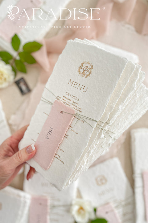 These handmade paper wedding menus capture the essence of fine art romance and luxury craftsmanship. Each menu is meticulously created from 100% cotton rag paper, known for its naturally soft texture and deckled edges, creating an heirloom-quality keepsake for your wedding day. The design features a custom gold monogram crest printed in elegant metallic foil, paired with refined typography and delicate blush pink name tags, tied gracefully with natural twine for a personal, layered touch.