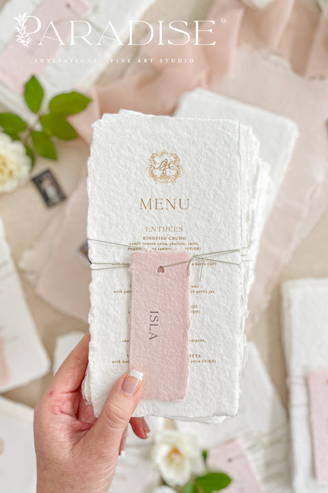 These handmade paper wedding menus capture the essence of fine art romance and luxury craftsmanship. Each menu is meticulously created from 100% cotton rag paper, known for its naturally soft texture and deckled edges, creating an heirloom-quality keepsake for your wedding day. The design features a custom gold monogram crest printed in elegant metallic foil, paired with refined typography and delicate blush pink name tags, tied gracefully with natural twine for a personal, layered touch.