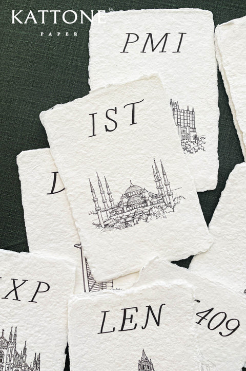 Close up of cotton paper place card showing textured surface, deckled edges and detailed building illustration.