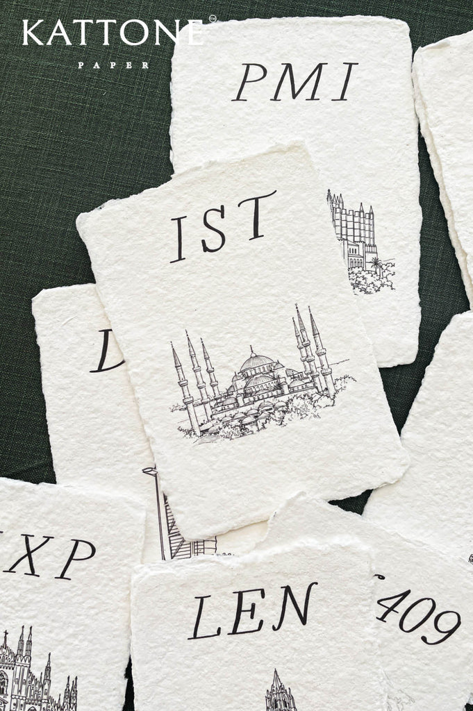 Close up of cotton paper place card showing textured surface, deckled edges and detailed building illustration.