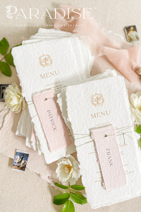 These handmade paper wedding menus capture the essence of fine art romance and luxury craftsmanship. Each menu is meticulously created from 100% cotton rag paper, known for its naturally soft texture and deckled edges, creating an heirloom-quality keepsake for your wedding day. The design features a custom gold monogram crest printed in elegant metallic foil, paired with refined typography and delicate blush pink name tags, tied gracefully with natural twine for a personal, layered touch.