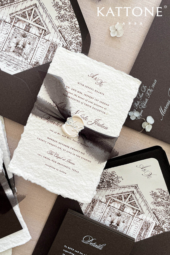Luxury handmade paper wedding invitation suite with deep espresso envelopes, chapel illustration liners, black ribbon, and wax seal.