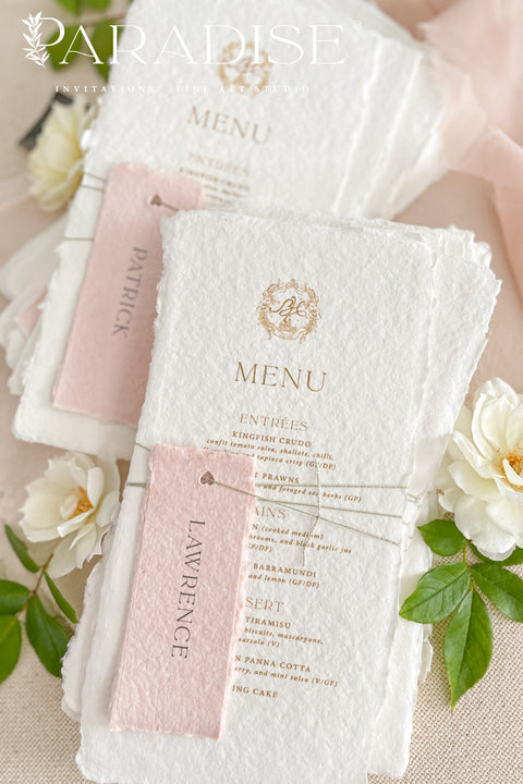 These handmade paper wedding menus capture the essence of fine art romance and luxury craftsmanship. Each menu is meticulously created from 100% cotton rag paper, known for its naturally soft texture and deckled edges, creating an heirloom-quality keepsake for your wedding day. The design features a custom gold monogram crest printed in elegant metallic foil, paired with refined typography and delicate blush pink name tags, tied gracefully with natural twine for a personal, layered touch.