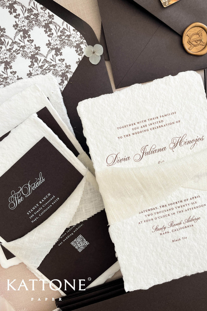 Close up of handmade cotton paper invitation highlighting textured deckled edges, soft chiffon ribbon and refined typography.
