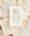Overhead flat lay of an elegant Sicily-inspired wedding invitation suite featuring ivory handmade paper invitations with coastal watercolor illustrations, champagne envelopes with matching Mediterranean cliff envelope liners, and warm beige handmade paper wedding details cards tied with delicate ivory lace bows. The stationery is arranged on natural linen with soft romantic lace accents.