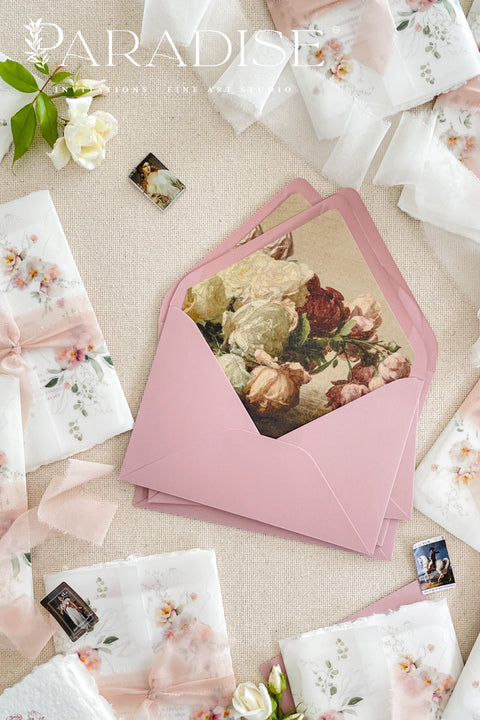 Rose pink wedding envelopes with floral envelope liners styled on neutral linen with silk ribbon, floral accents, and fine art stationery details.